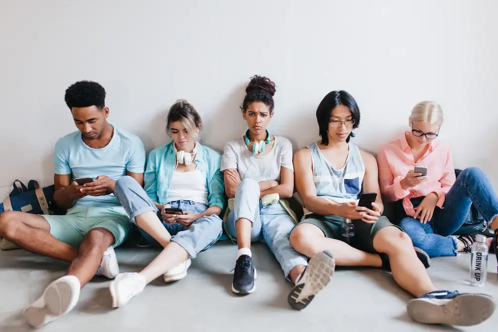 Friends sit looking at their phones